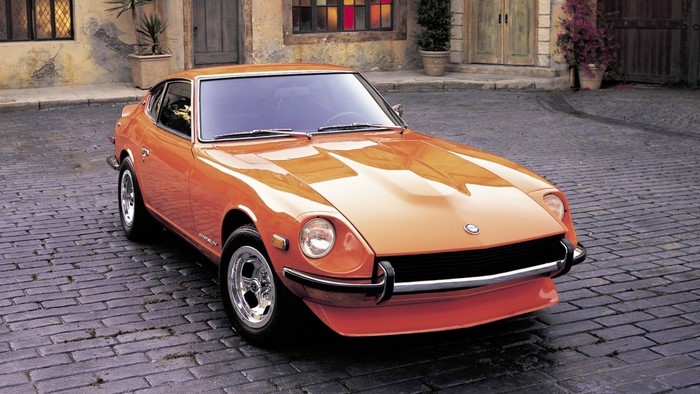 Orange Datsun 240Z sports car parked on cobblestone street