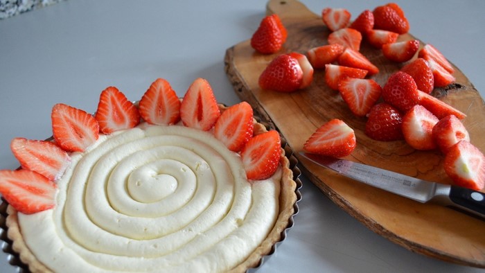 Strawberry tart with whipped cream and sliced strawberries