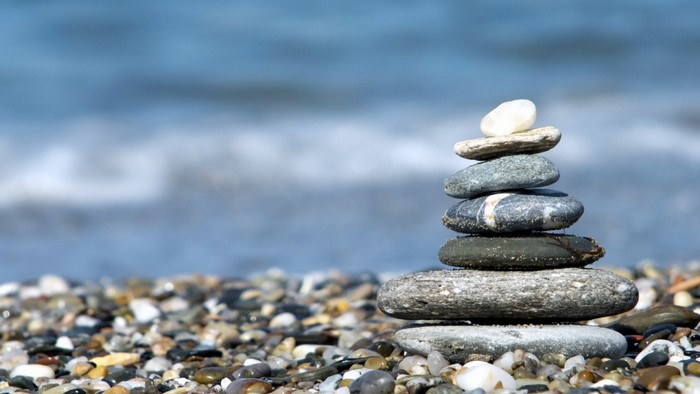 Stack of balanced stones on a pebble beach with the sea in the background