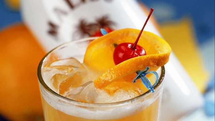 Malibu cocktail with orange and cherry garnish