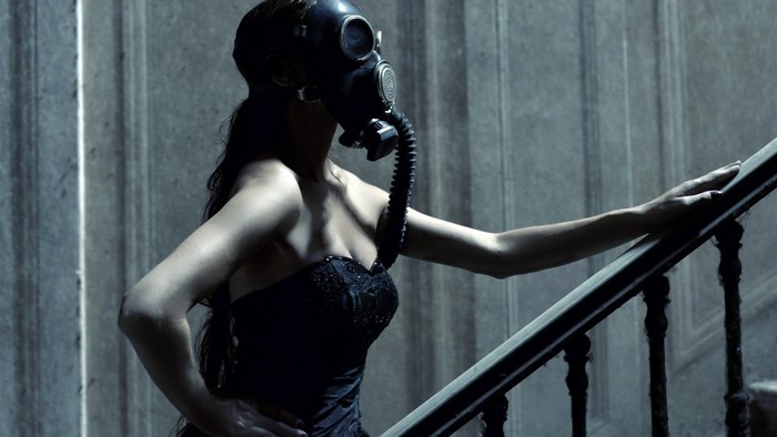 Woman in black dress wearing gas mask on stairs