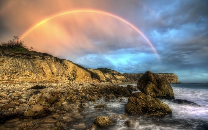 Rainbow over a rocky beach and cliffs