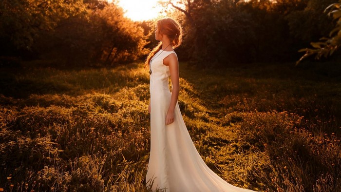 Woman in white dress in a sunlit meadow