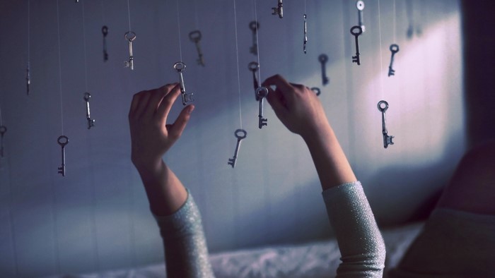 Hands reaching for keys hanging from strings