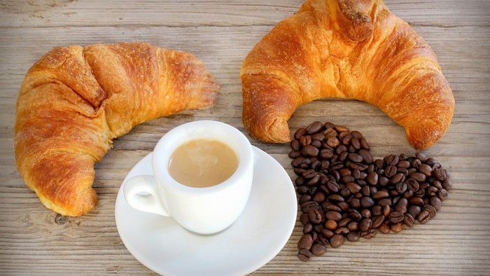 Croissants and coffee with coffee beans in a heart shape