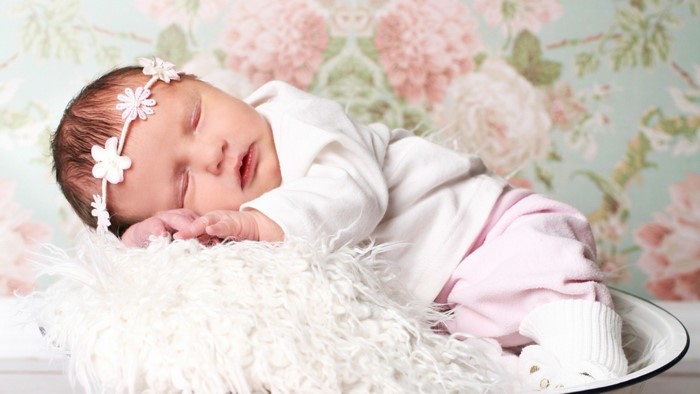 Newborn baby girl sleeping with flower headband