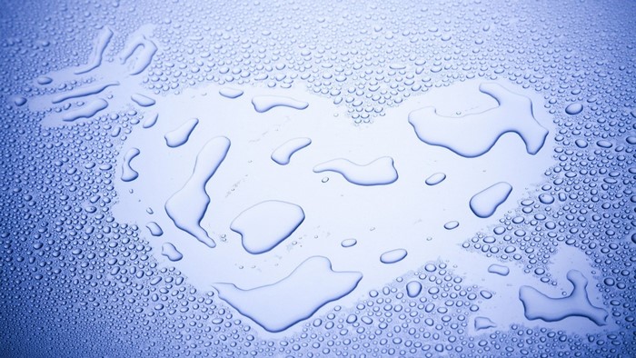 Water drops forming a heart shape on a blue surface