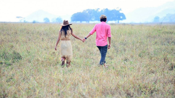 Couple holding hands walking in a grassy field