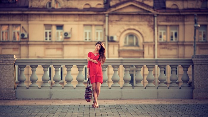 Woman in red dress holding a bag on a balcony