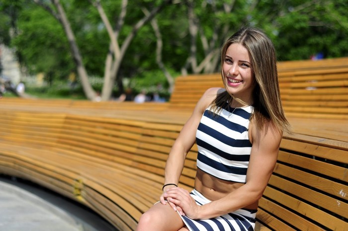 Woman in striped outfit sitting on a wooden bench