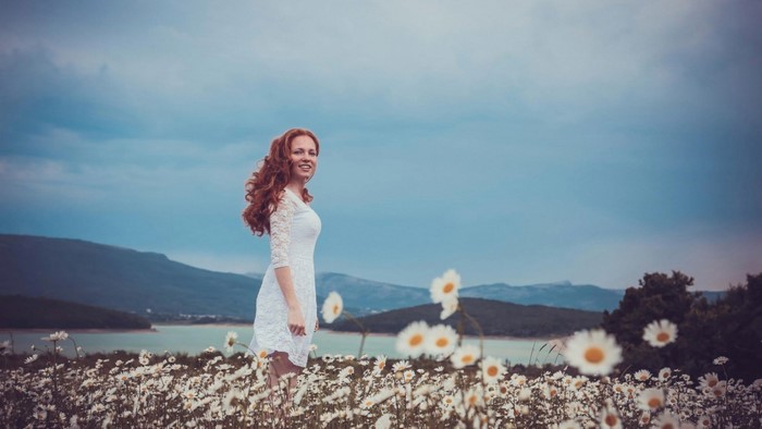 Woman in white dress in a field of daisies