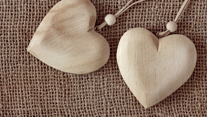 Two wooden heart pendants on burlap
