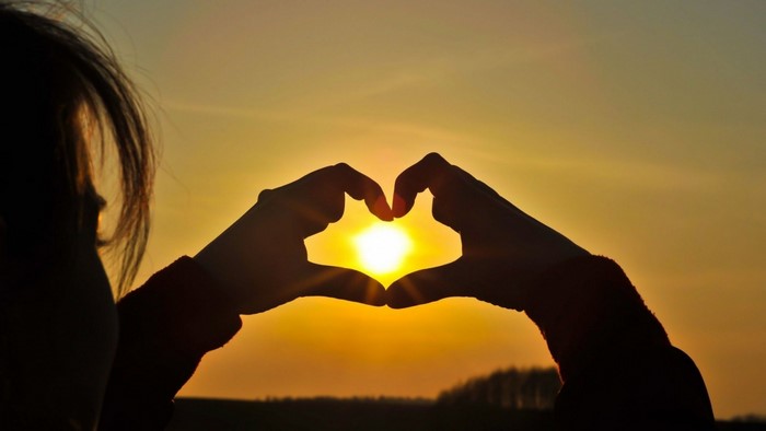 Silhouette of hands forming a heart at sunset