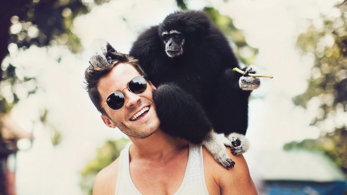 Man with sunglasses and a gibbon monkey on his shoulder