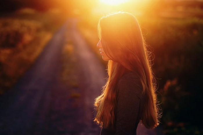 Woman with long hair in sunset light on a road