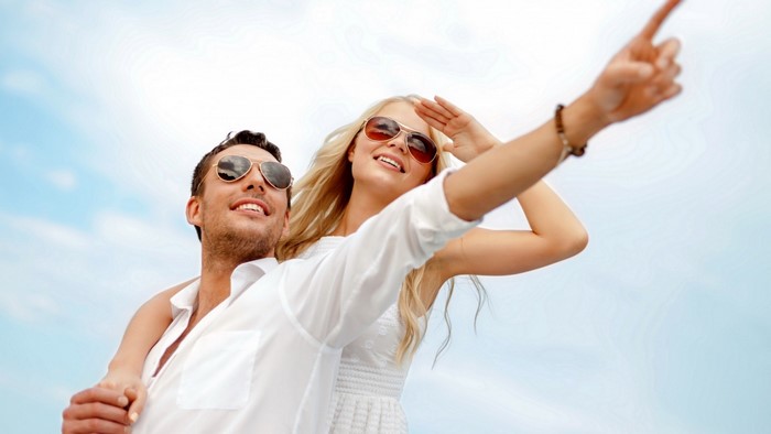 Couple in sunglasses pointing at the sky