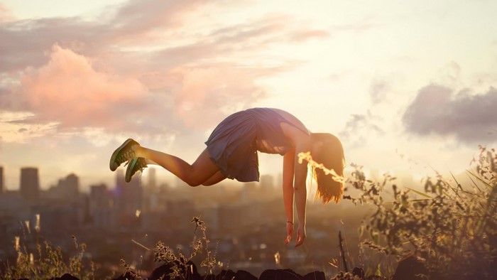 Woman floating in the air at sunset