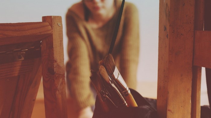 Woman with paintbrushes in front of easel