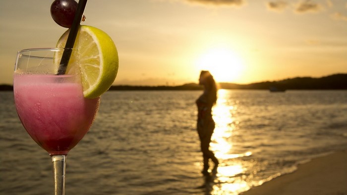 Pink cocktail with lime and grape at sunset