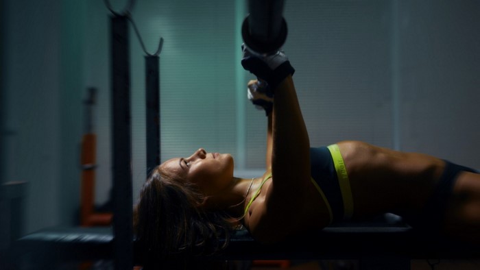 Woman performing bench press in a gym