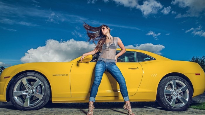 Woman posing with a yellow Chevrolet Camaro
