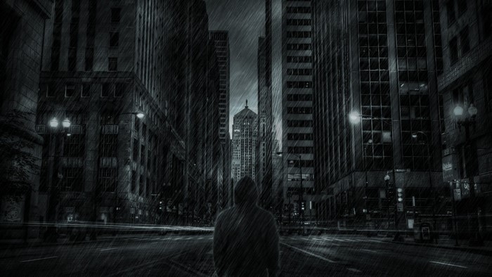 Person standing in a rainy city at night