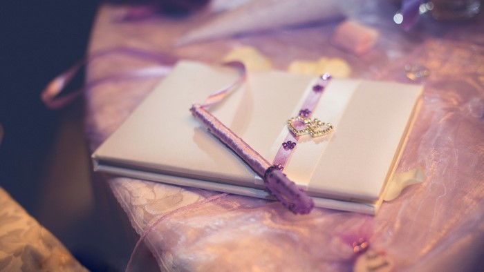 White guest book with purple pen and heart charm