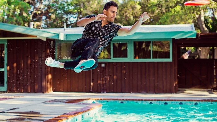 Channing Tatum playing frisbee by a swimming pool