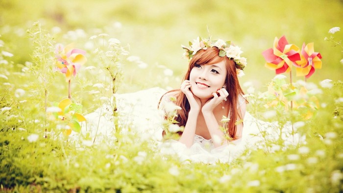Asian woman with flower crown in a meadow with pinwheels