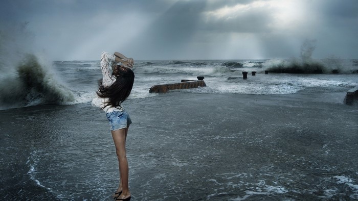 Woman in shorts by stormy ocean waves