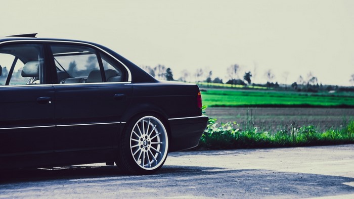 Dark BMW Sedan parked on a road with a field