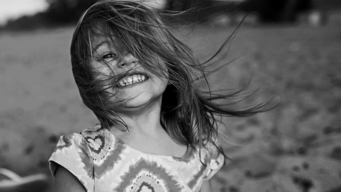 Black and white portrait of a smiling girl with windblown hair