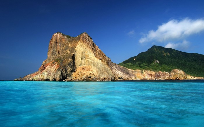 Rocky island with green mountain in turquoise sea