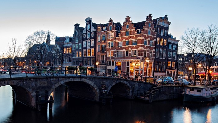Amsterdam canal with historic buildings and bridge at dusk