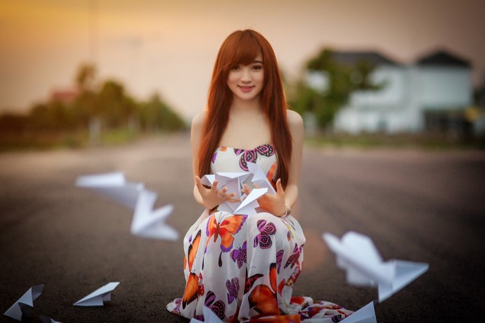 Young woman with red hair holding paper planes