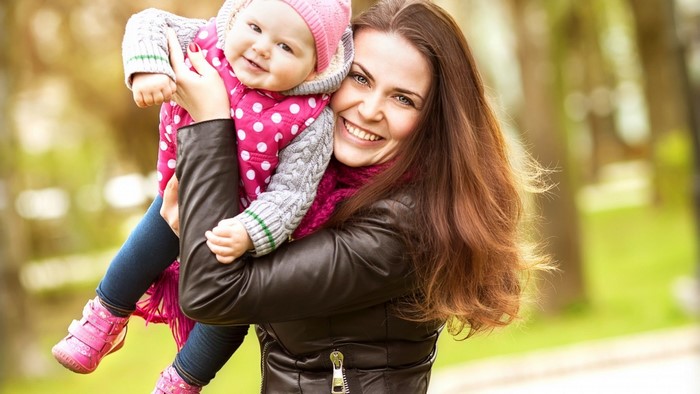 Mother holding her smiling baby daughter outdoors