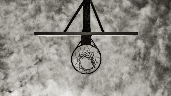 Basketball hoop viewed from below against cloudy sky