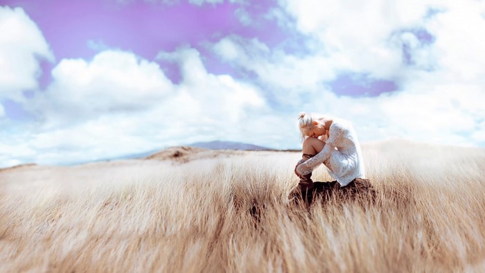 Woman in white dress sitting in a field