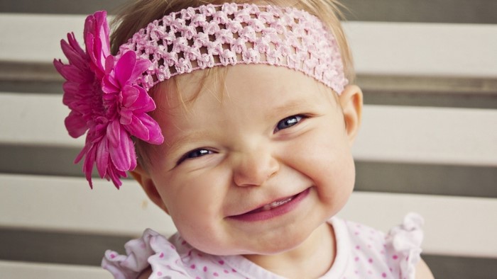 Baby girl with pink flower headband smiling