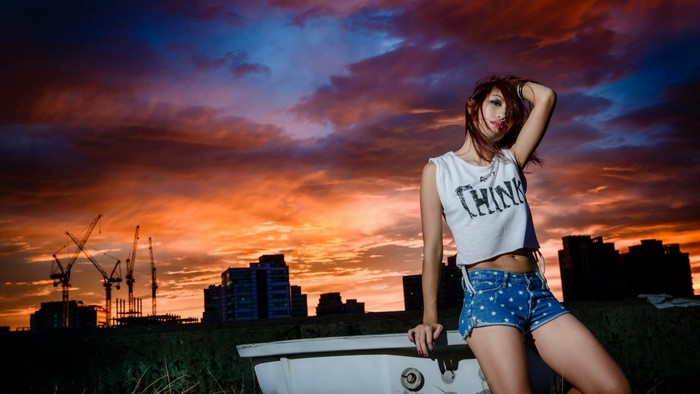 Woman in shorts posing by bathtub at sunset