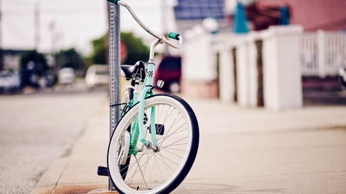 Mint green bicycle parked on a sidewalk