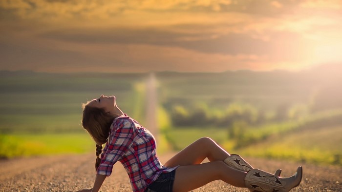 Woman in Plaid Shirt and Boots on Road at Sunset