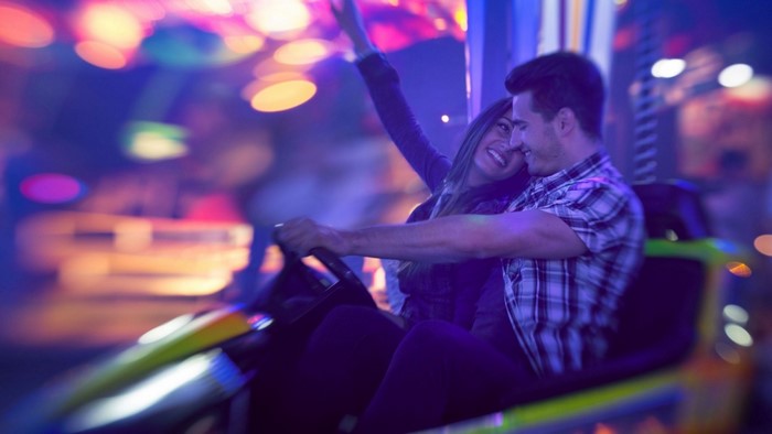 Couple enjoying a ride at a colorful amusement park at night