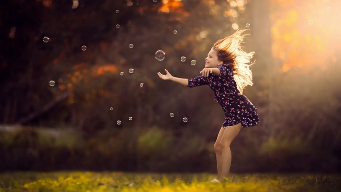 Girl playing with bubbles in sunlight