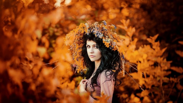 Woman with a flower wreath in autumn foliage