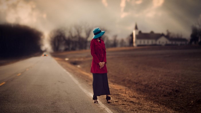 Woman in red coat and blue hat on a road