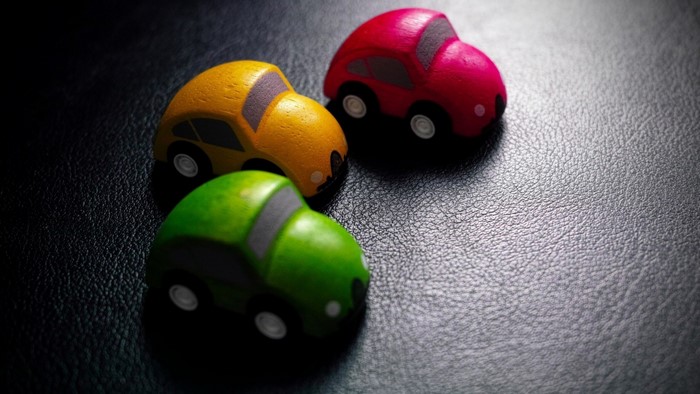 Three colorful wooden toy cars on a black surface
