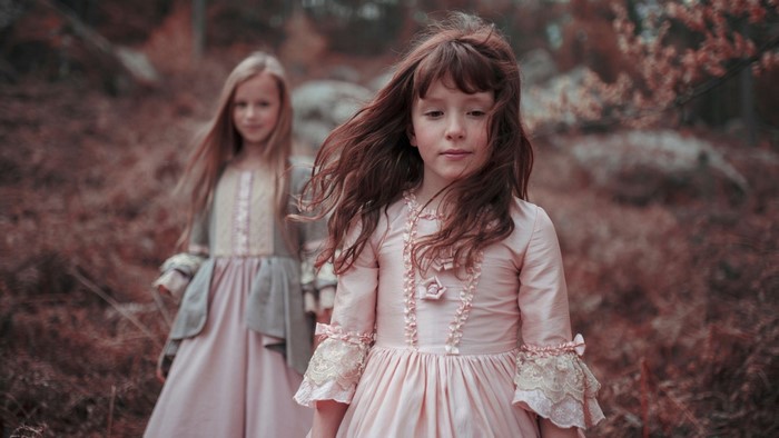 Two girls in vintage dresses in an autumn forest