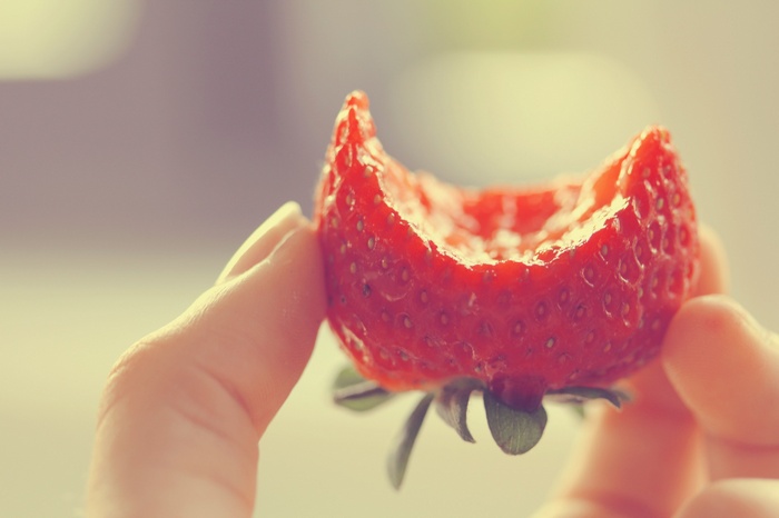 Hand holding a bitten strawberry