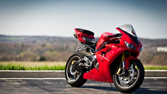Red Triumph Daytona motorcycle parked on asphalt